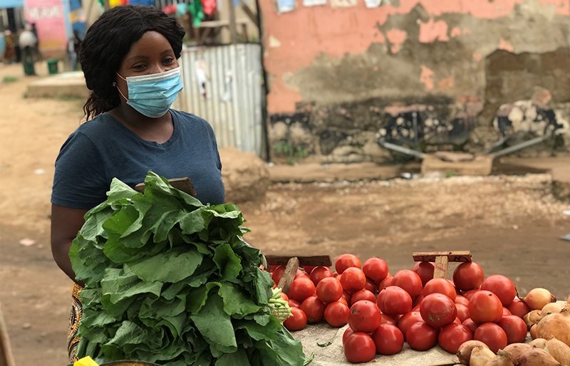 A woman wearing a face mask holding vegetables